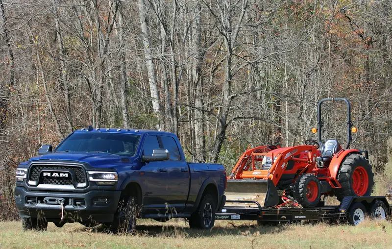 Work truck towing a compact tractor to a job site